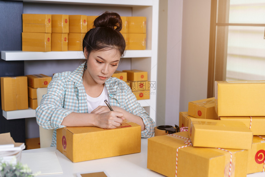 年轻女创业者在包裹箱线商业分娩前准备工作上写图片