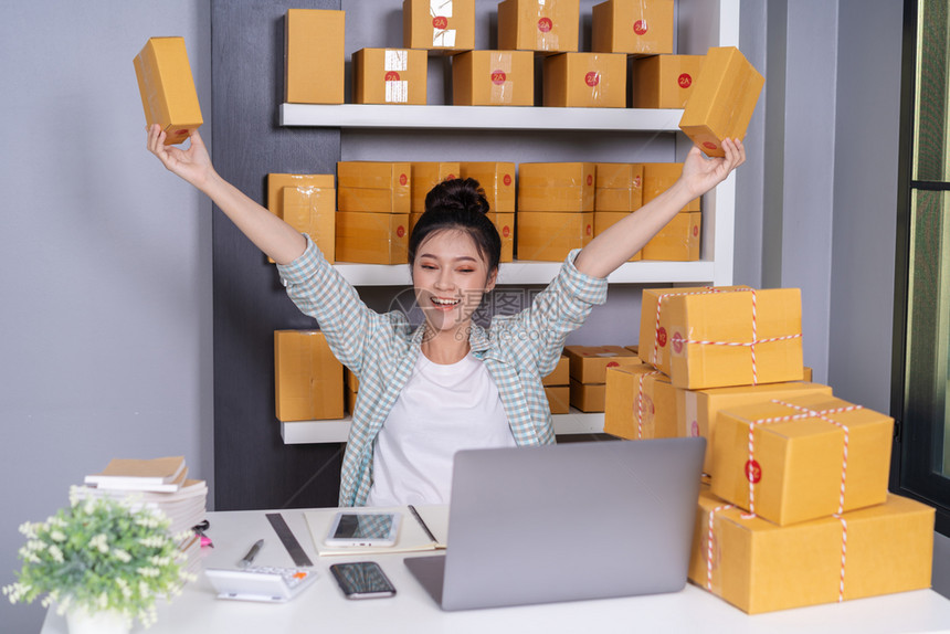 成功的青年女企业家在庭办公室用包裹箱在自己的工作购物网上图片