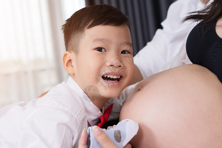 怀着孕期母亲的肚子抱着快乐男孩图片