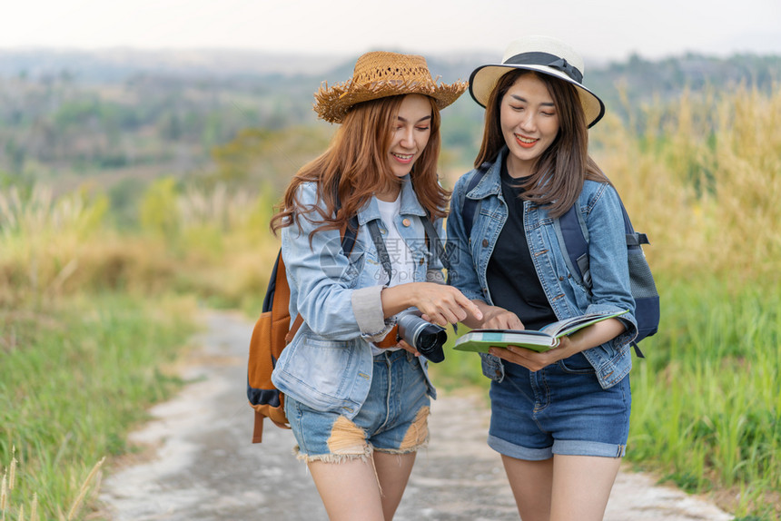 2名妇女旅行者在时地点图上搜索方向图片