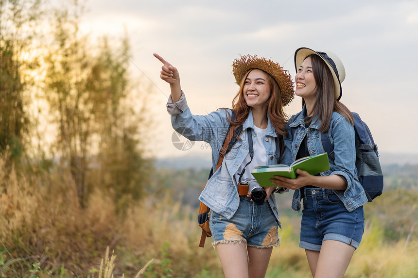 2名妇女旅行者在时地点图上搜索方向图片