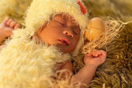 身着鸡装的新生婴儿睡在毛皮床上图片