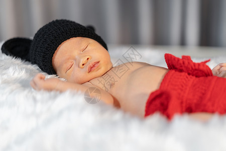 穿着老鼠服装的新生婴儿睡在毛皮床上背景图片