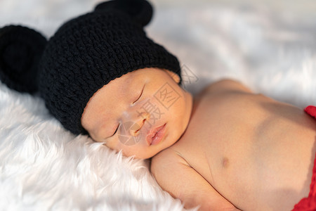 穿着老鼠服装的新生婴儿睡在毛皮床上图片