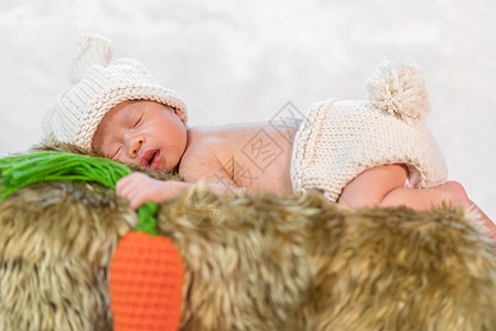穿着兔子服装的新生儿婴睡在毛皮床上高清图片