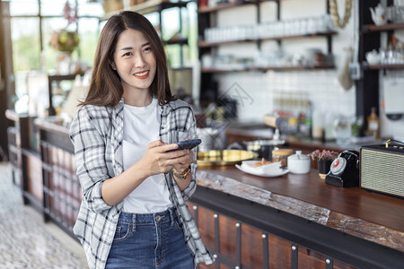 在咖啡馆里使用智能手机的快乐女人图片