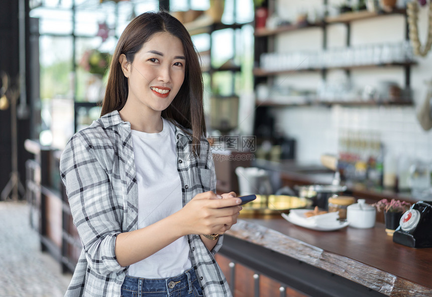 在咖啡馆里使用智能手机的快乐女人图片