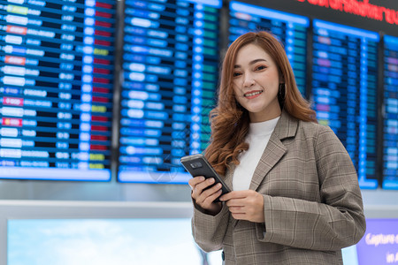 在机场与飞行信息板使用智能手机图片