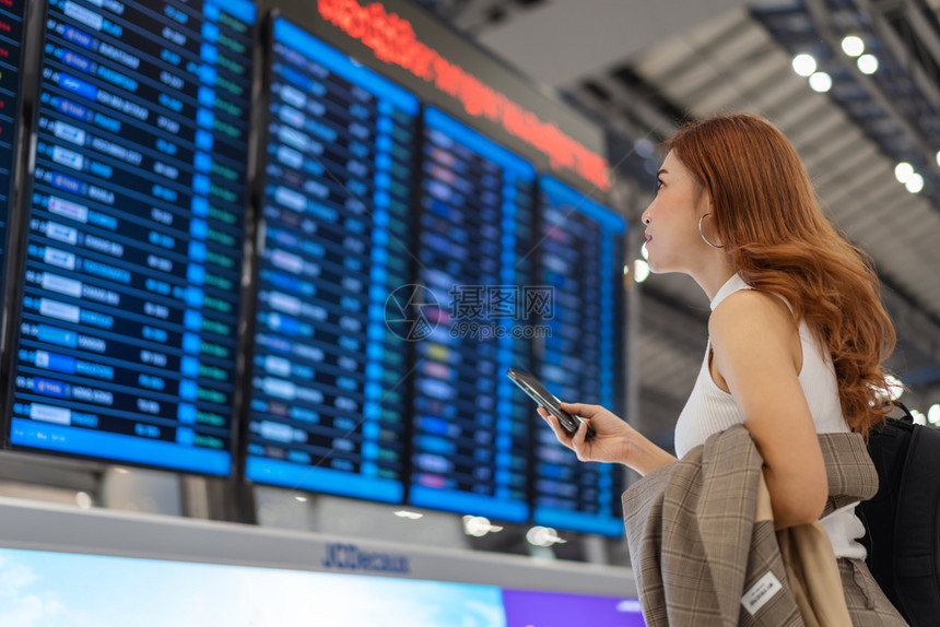 在机场与飞行信息板使用智能手机图片