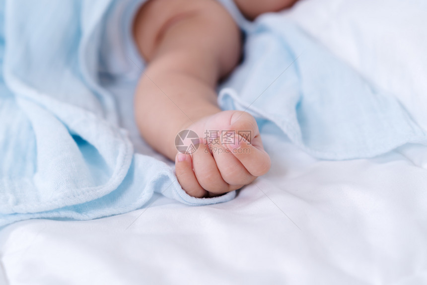 在床上紧握着婴儿手的图片