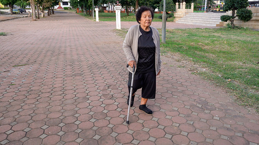 高级妇女在公园中带着拐杖走来去背景图片