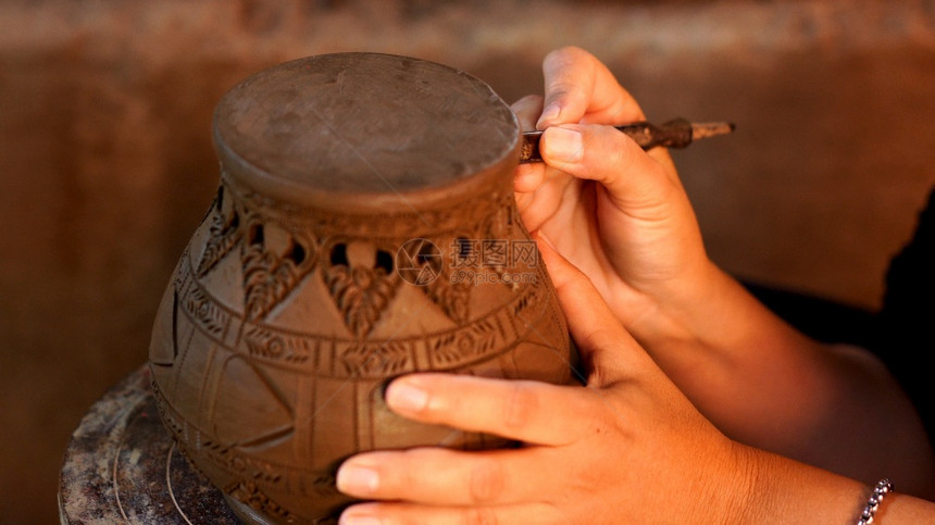 手使陶器在土上造成装饰图案图片
