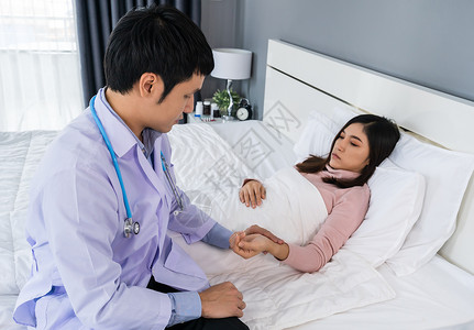 生病的妇女躺在床上医生检查她的脉搏图片