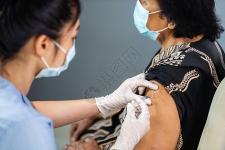 戴医用面具的医生给病人注射疫苗图片