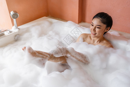 年轻女青放松在浴缸用泡沫洗浴图片