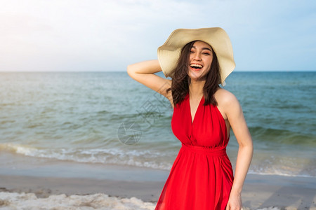 穿着红裙子的开心女人在海边享受着高清图片