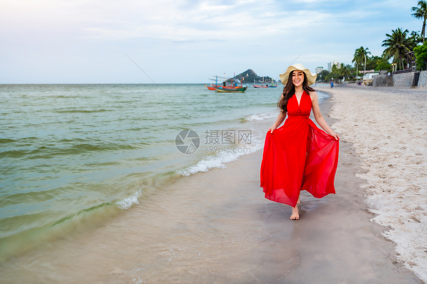 穿着红裙子的开心女人在海边散步图片