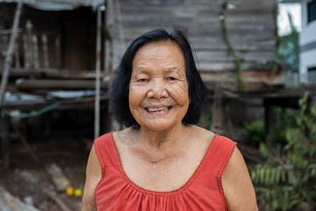 穿着圆颈无袖领的泰籍老年妇女在旧木屋中笑图片