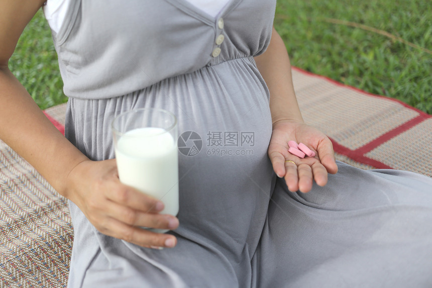 孕妇手里有一杯牛奶和维生素药丸图片