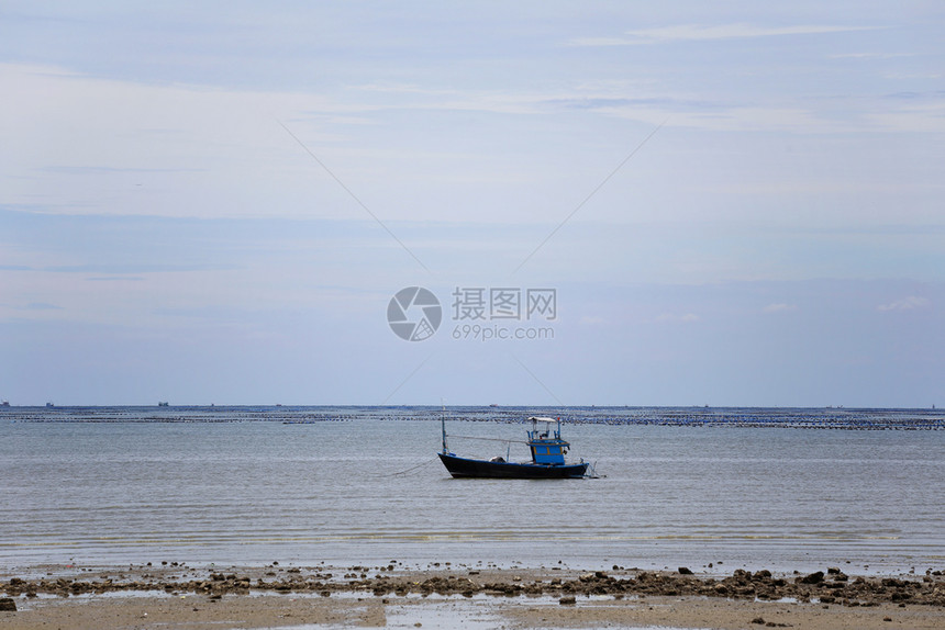 在海岸沿的小型渔船潮汐低和天空背景图片