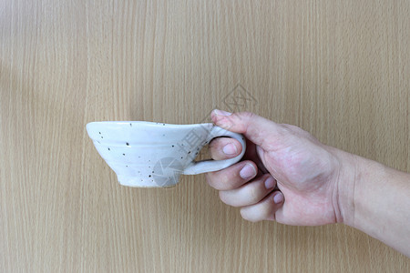白杯手握着木材背景用于设计概念食物图片