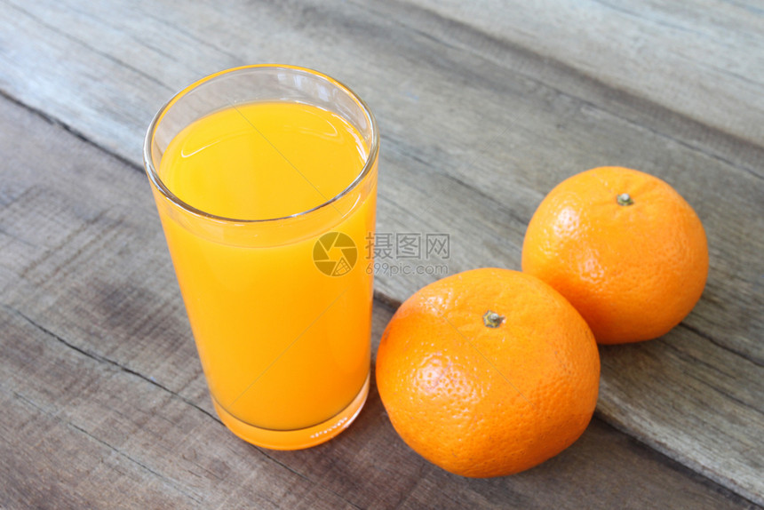 放在木制地板上的新鲜橙子水果在玻璃里有汁用于健康饮食的概念图片