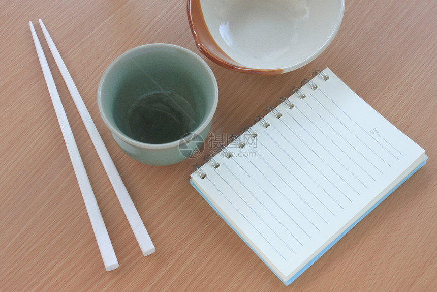 木质纸碗和白筷子放在书边的木本上用来设计食物概念图片