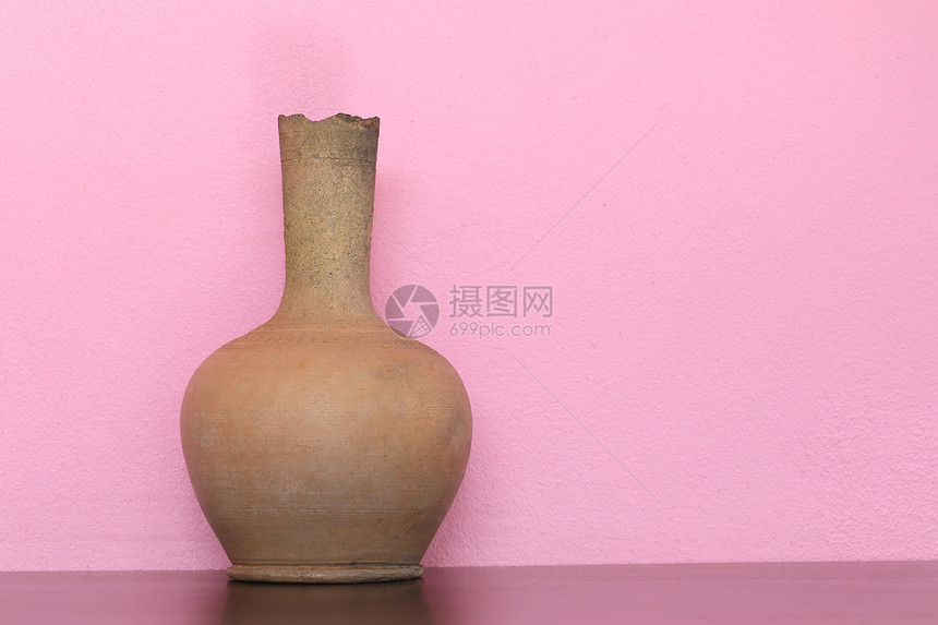 棕色的花瓶在木制桌子上粉红色的壁底图片