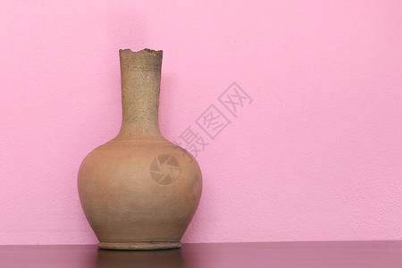 棕色的花瓶在木制桌子上粉红色的壁底背景图片