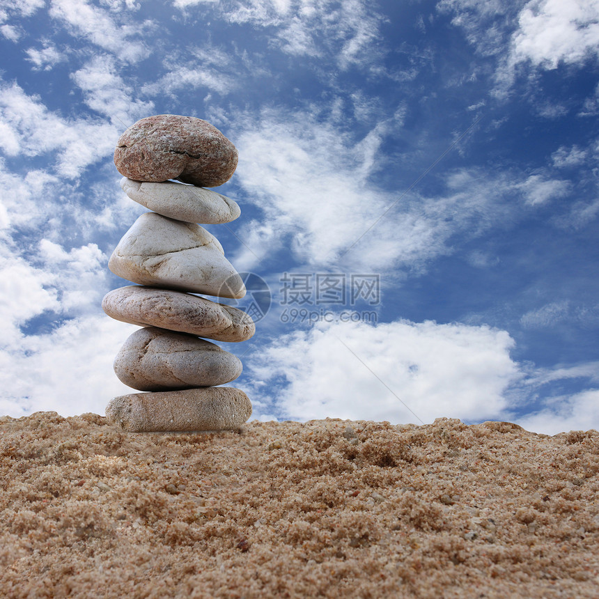 沙子上的平衡石和蓝天空背景图片