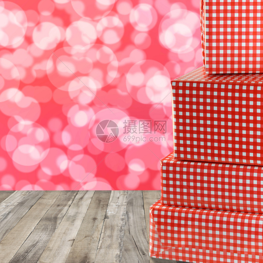 红礼盒堆在木地板上红色的bokeh抽象背景图片
