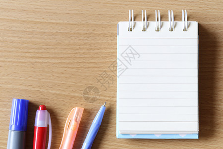 空白的笔记本和木制地板背景的笔用于设计你的工作概念图片