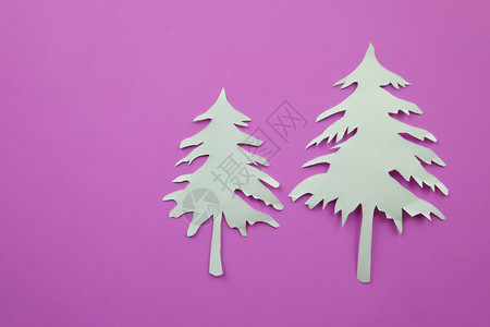 写在粉红纸背景上的圣诞树白纸形状用来设计你节日的概念背景图片