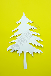 黄纸背景上的圣诞树白纸形状用来设计你的节日概念图片