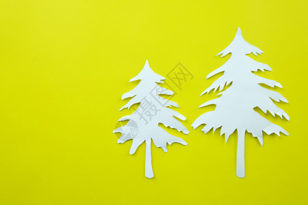 黄纸背景上的圣诞树白纸形状用来设计你的节日概念图片
