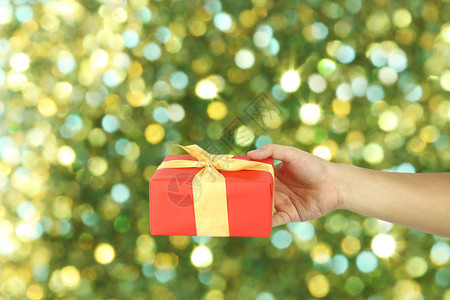 红礼物盒手握着圣诞节的概念绿色模糊的bokeh背景设计你的工作图片