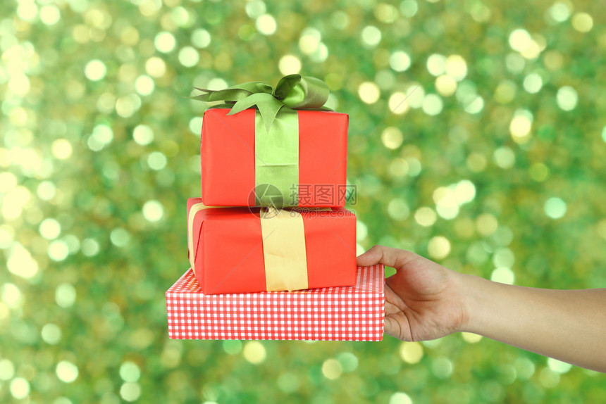 红礼物盒手握着圣诞节的概念绿色模糊的bokeh背景设计你的工作图片