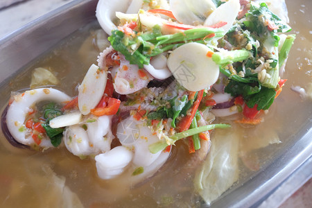 蒸汽鱿鱼和泰国海鲜柠檬放在木制桌上的锅里图片