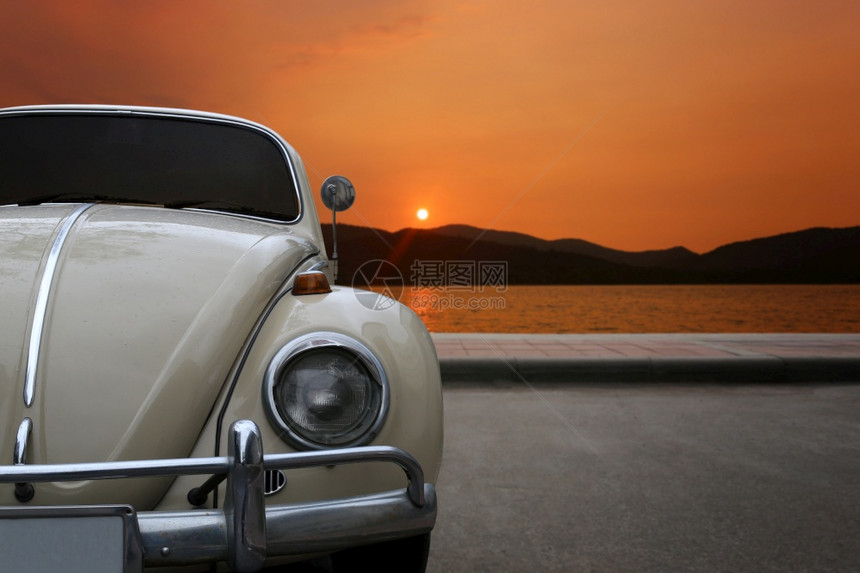 古典车停在沿海波浪防护区日落的黄昏天空图片