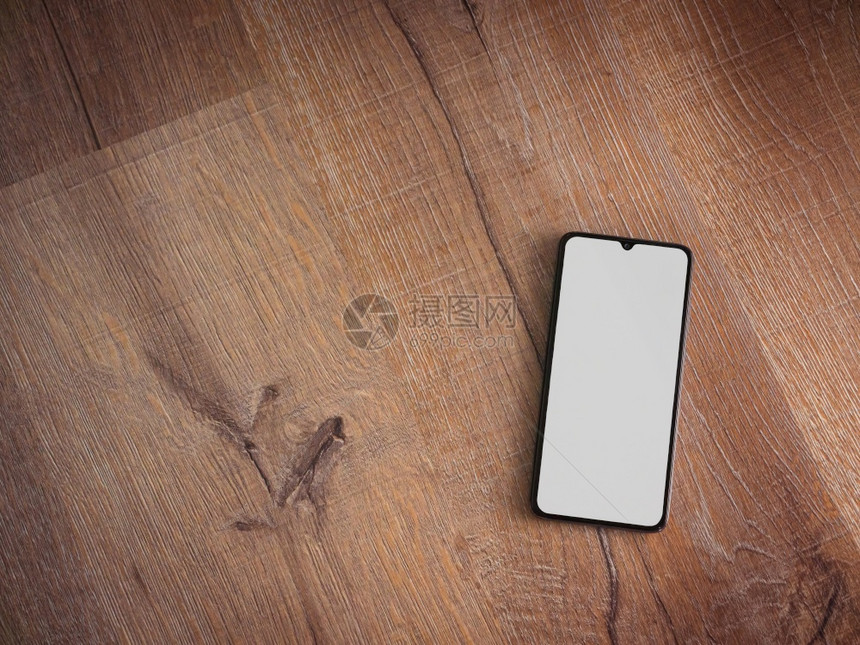 黑色移动智能手机模型位于表面在木制背景上隔开空白的屏幕顶端视图平面上有复制空间图片