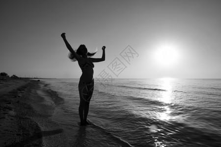 一个女孩在海边夕阳下的剪影大海夕阳映衬下的黑影晚上海滩上的女孩海边夕阳映衬下的女孩剪影背景图片