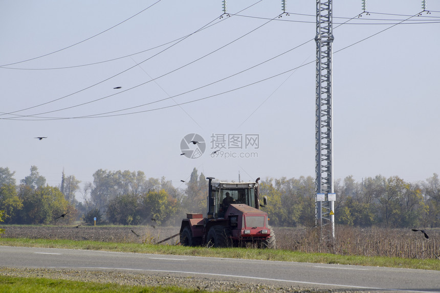 拖拉机在田里耕种乌鸦在他周围飞来去寻找食物拖拉机在田里耕种乌鸦在他周围飞去寻找食物图片