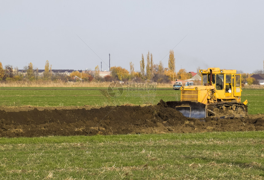 黄色拖拉机带有附的凝胶在地面平整排水系统上工作在地面平整图片