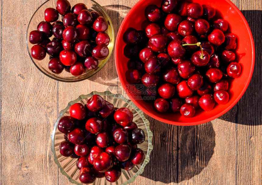 一种甜樱桃的浆果放在塑料杯的木制背景上成熟的红甜樱桃一种甜樱桃的浆果放在塑料杯的木制背景上成熟的红甜樱桃图片