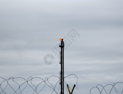 湮灭油田上的火炬系统燃烧通过火炬头燃烧在油田上的火炬系统背景