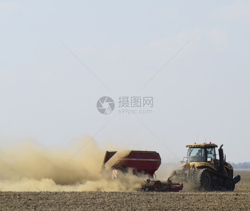 俄罗斯TemryukTemryuk2015年7月9日拖拉机在田里骑马把肥料放入土壤干拖拉机车产生的尘云耕田之后的肥料拖拉机在田里图片