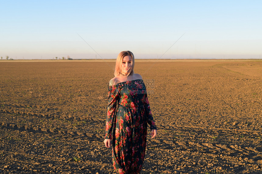 穿着日落背景的红黑礼服女人图片