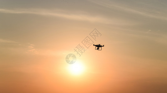 日落背景下的无人驾驶飞机在空中飞行高清图片