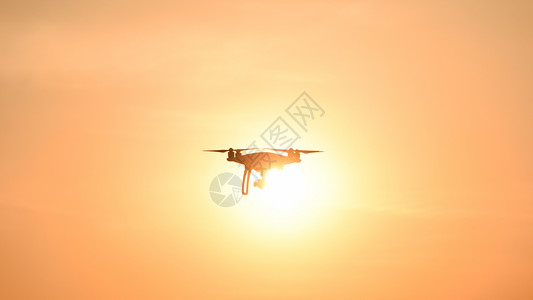 日落背景下的无人驾驶飞机在空中飞行图片