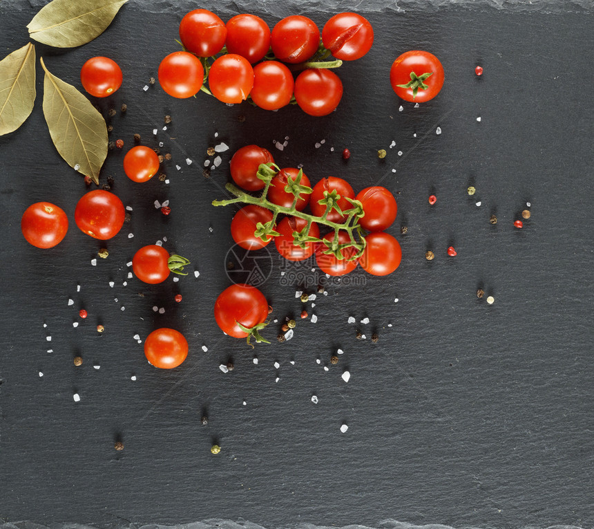 树枝上的红樱桃番茄洒满盐和胡椒黑色石墨背景图片